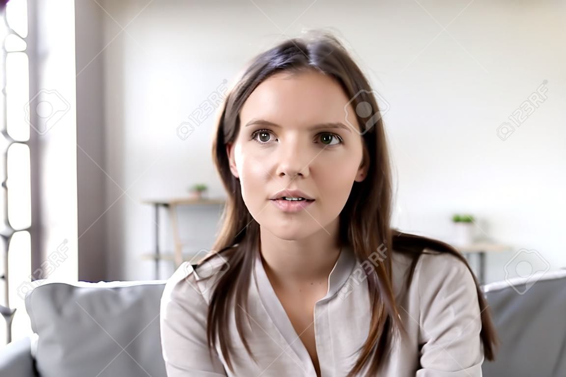 Kopfschuss Porträt junge Frau sitzt auf der Couch und schaut in die Kamera, die sich mit der modernen Computer-Webcam-Technologie unterhält, die mit einem Freund spricht, Mädchen, das Vlog aufzeichnet, das ein Vorstellungsgespräch aus der Ferne führt