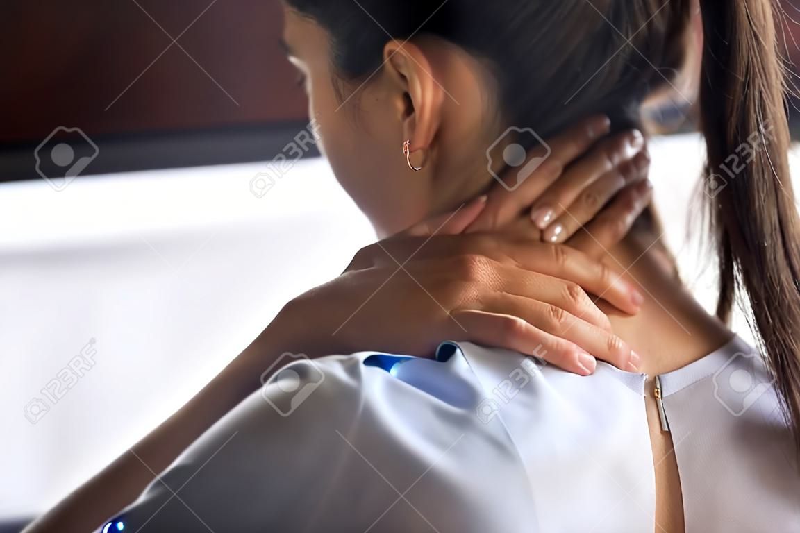 Tired woman massaging rubbing stiff sore neck tensed muscles fatigued from computer work in incorrect posture feeling hurt joint shoulder back pain ache, fibromyalgia concept, close up rear view