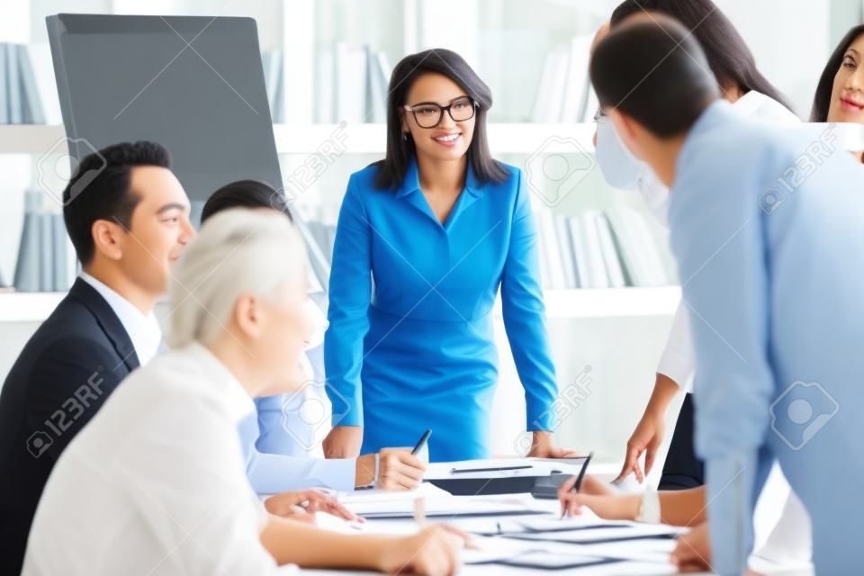 Multi-ethnic team members takes part in briefing lead by aged businesswoman company boss, businesspeople feels satisfied succeed agreement acceptable to both parties, mentoring or negotiations concept