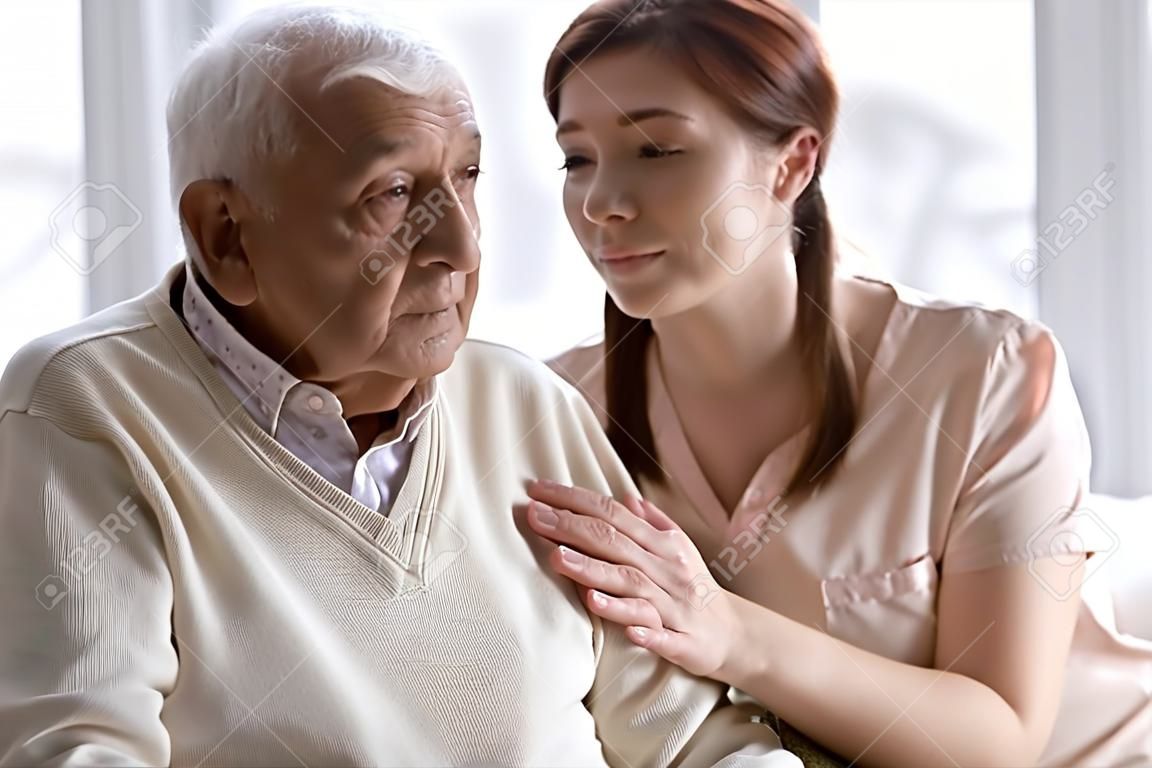 La nipote adulta premurosa esprime simpatia accarezzando il nonno anziano correlato alla perdita di memoria della malattia senile, al disturbo mentale o alla demenza. Concetto di casa di cura per anziani di generazioni di caregiving