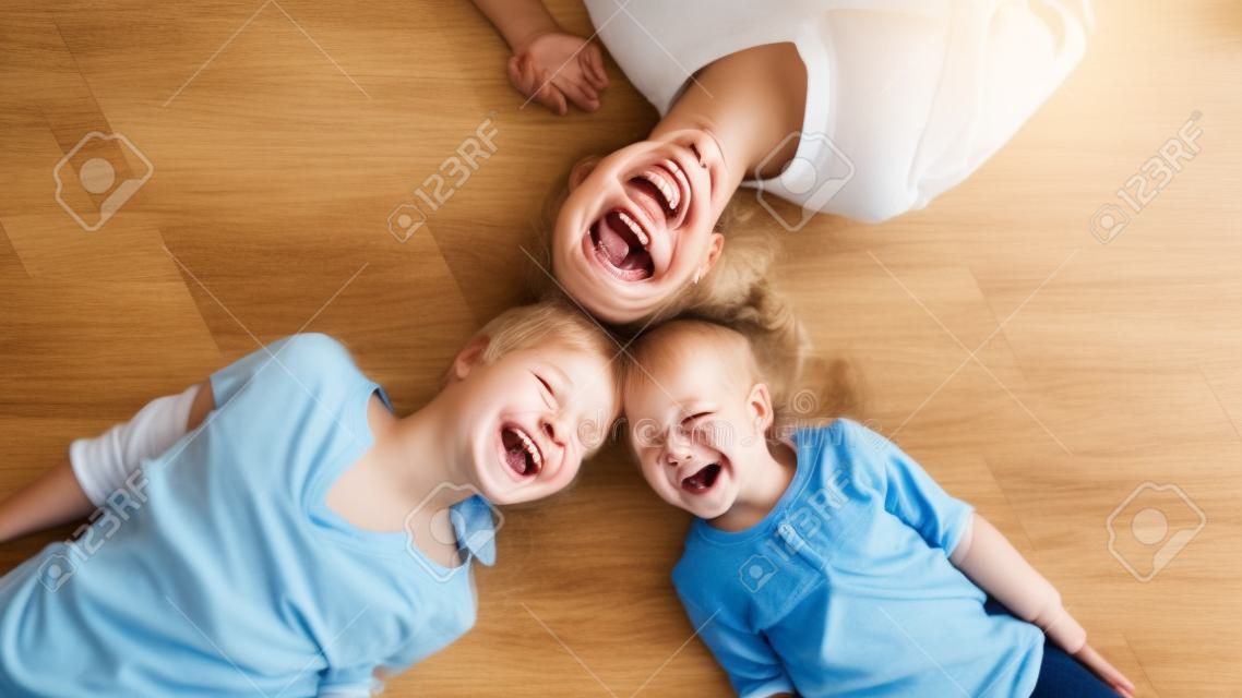 Draufsichtporträt von lächelnden drei generationen von frauen, die zu hause auf einem warmen holzboden liegen und zusammen spaß haben, überglückliches mädchen mit junger mutter und älterer großmutter entspannen sich am familienwochenende