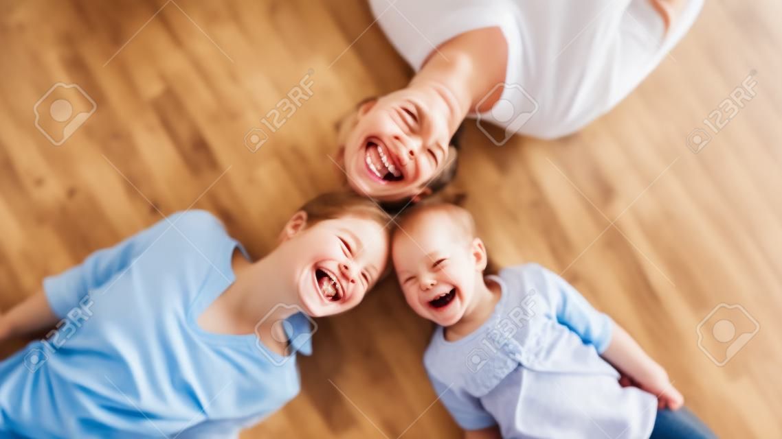 Draufsichtporträt von lächelnden drei generationen von frauen, die zu hause auf einem warmen holzboden liegen und zusammen spaß haben, überglückliches mädchen mit junger mutter und älterer großmutter entspannen sich am familienwochenende