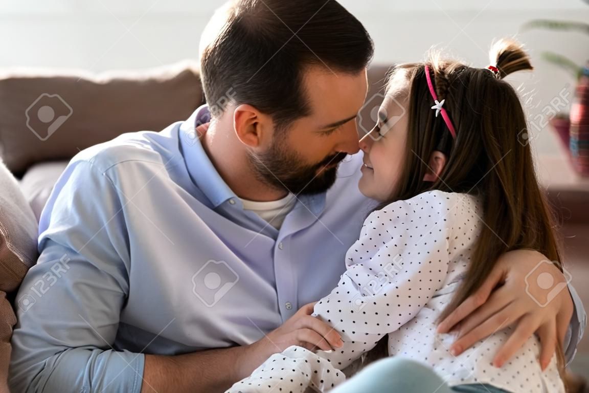 Caring young Caucasian father and little teenage daughter hug cuddle enjoy close intimate family moment at home together. Loving happy dad parent and teen girl child embrace share secrets.