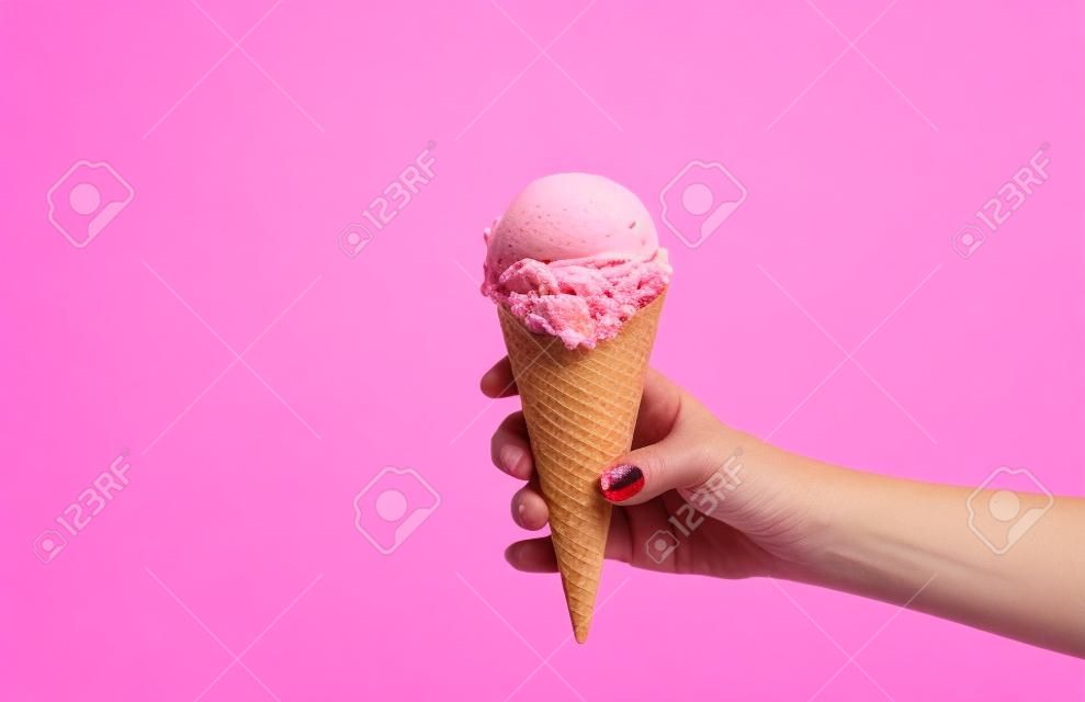 Hand holding strawberry ice cream cone on white background.  Strawberry ice cream in wafer cup.