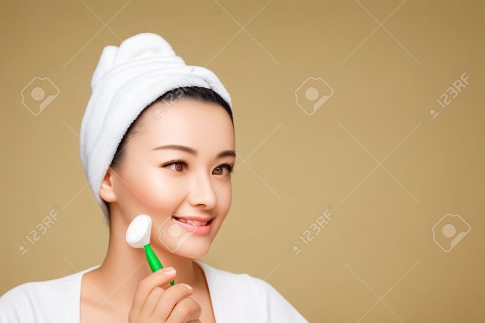 Face massage. Beautiful woman is getting massage face using jade facial roller for skin care, beauty treatment at home
