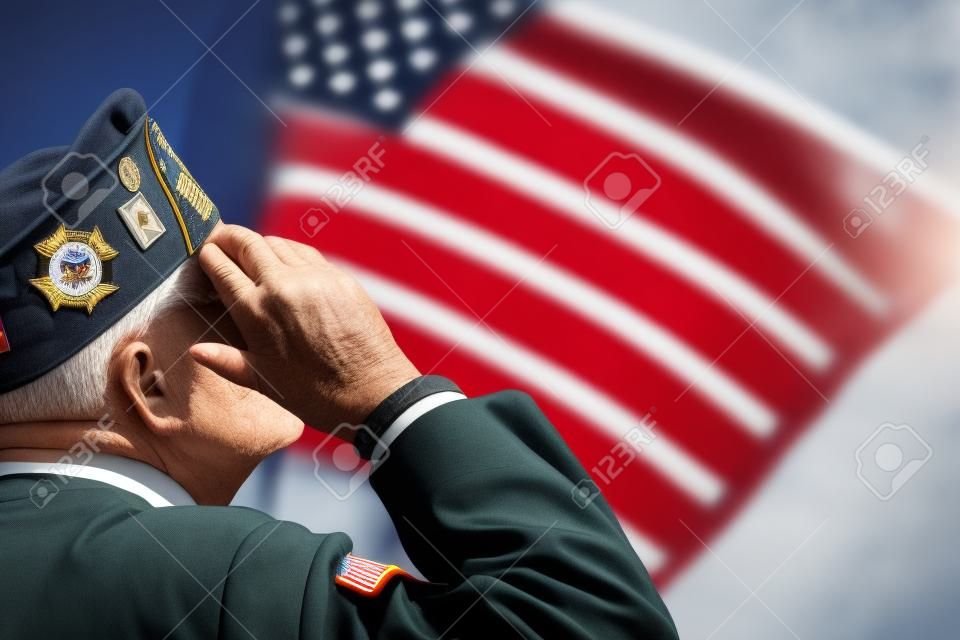 Ветеран является отдавая честь перед американским флагом.