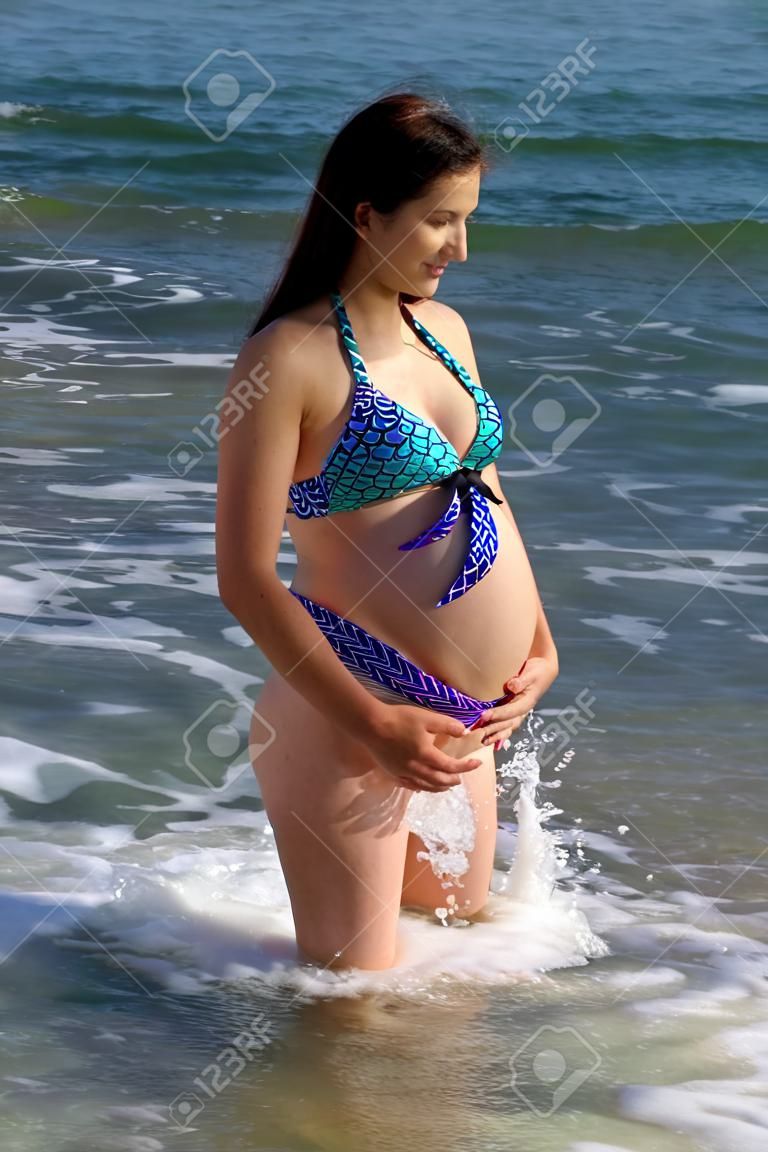 weibliches Model schwanger, die ihren Bauch im Wasser