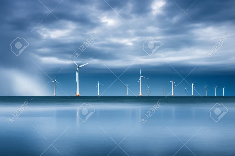 Przybrzeżny park wiatraków z burzowymi chmurami i błękitnym niebem, park wiatraków w oceanie. Holandia Europa