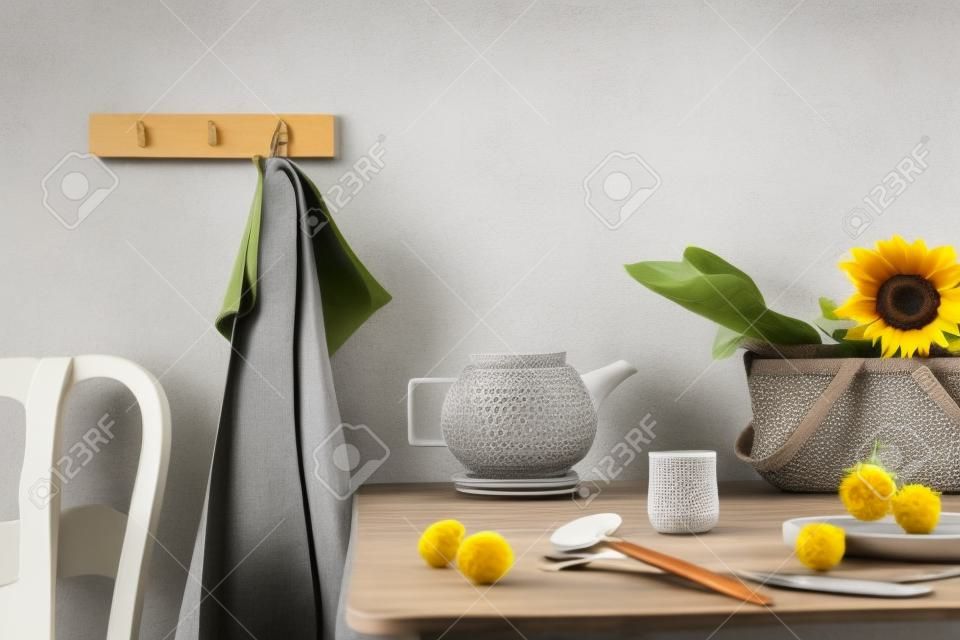 Cozy and stylish composition of creative dining room with copy space, wooden consola, sunflowers and personal accessories. Gray wall. Beautiful and sunny morning. Template.