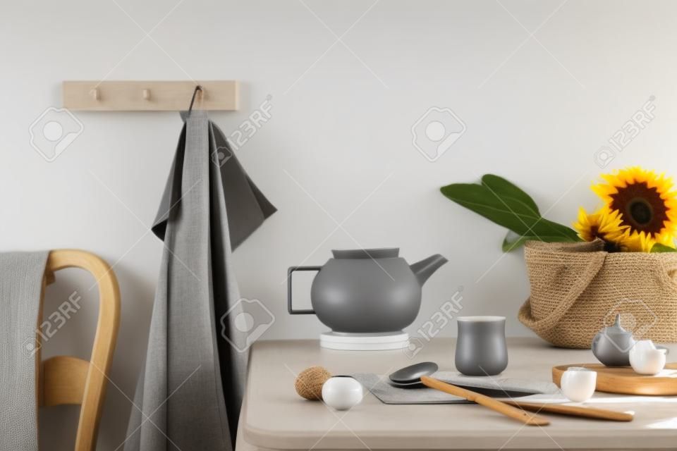 Cozy and stylish composition of creative dining room with copy space, wooden consola, sunflowers and personal accessories. Gray wall. Beautiful and sunny morning. Template.