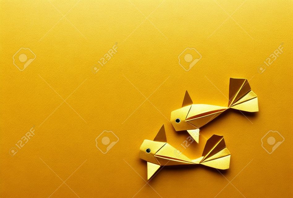Pesce fatto a mano della carpa a specchi di origami di colore dell'oro del mestiere di carta su fondo bianco con lo spazio della copia.