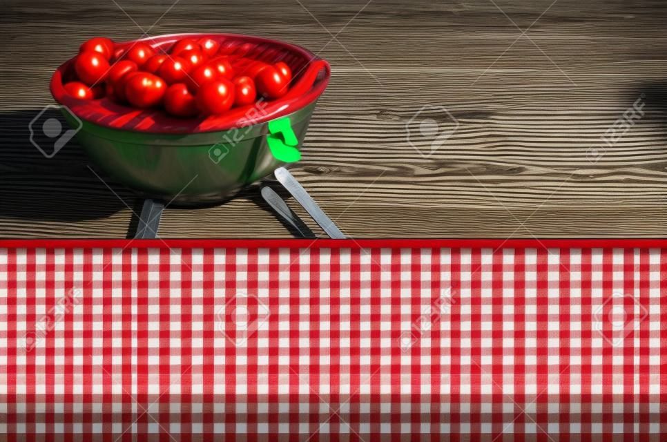 Пустой фон стол для пикника покрыт свежим стране красного и белого проверили ткань для размещения продукции или рекламы с барбекю на зеленой лужайке позади