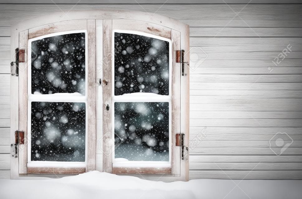 Kis mennyiségű hó a szüreti fa ablaküvegen a karácsonyi fények a házban.