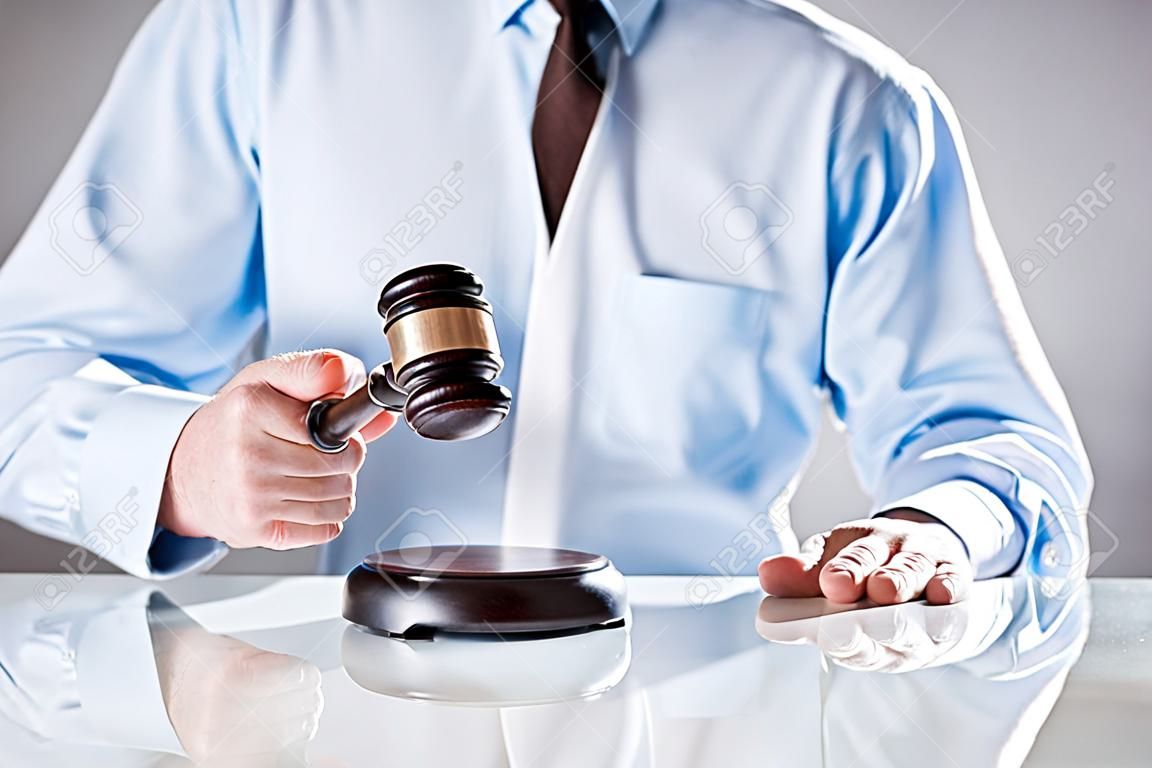 Адвокат, судья или аукционист поднимая деревянный молоток, чтобы судить или сбить продажи на торгах, крупным планом руки
