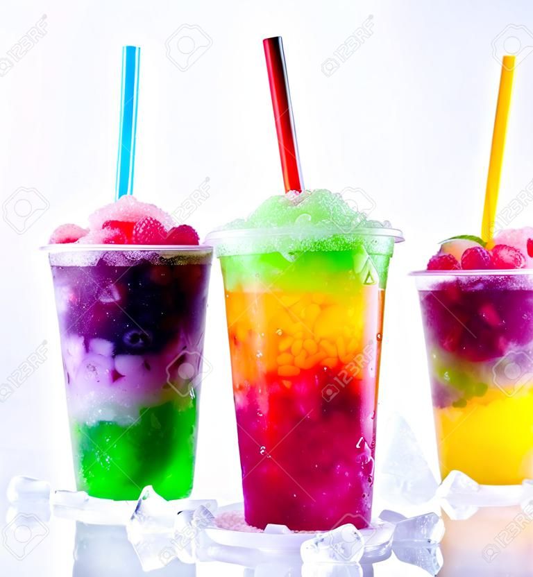 Todavía vida de primer plano del arco iris de colores en capas congeladas de frutas aguanieve bebidas dispuestas sobre hielo cubrió la superficie blanca de plástico para llevar Copas con las pajas de beber - Trío de refrescantes Granitas