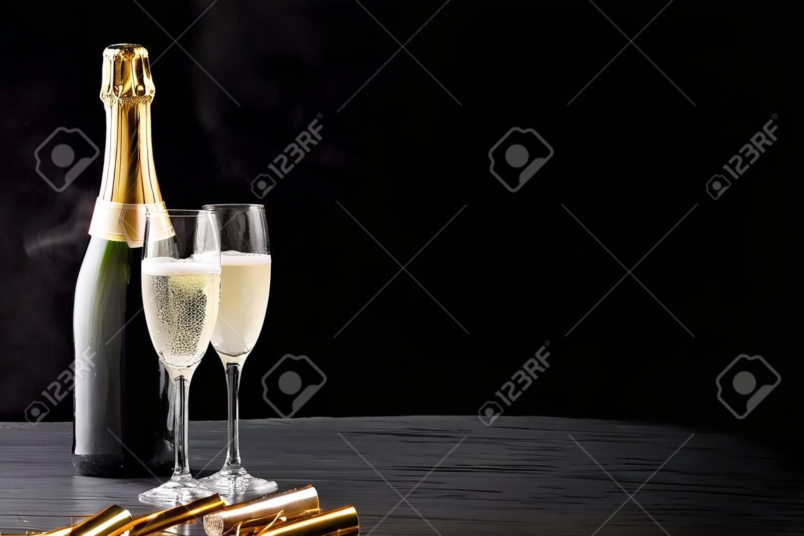 Champagne in ghiaccio per una festa romantica con le fiamme del partito d'oro ed eleganti flute di bollicine, lo spazio di copia su uno sfondo scuro