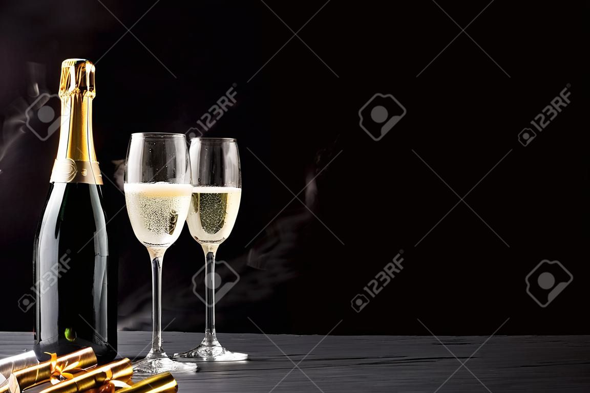 Funkelnder Champagner auf Eis für eine romantische Feier mit Goldpartyausläufern und eleganten Flöten des sprudelnden, Kopienraumes über einem dunklen Hintergrund