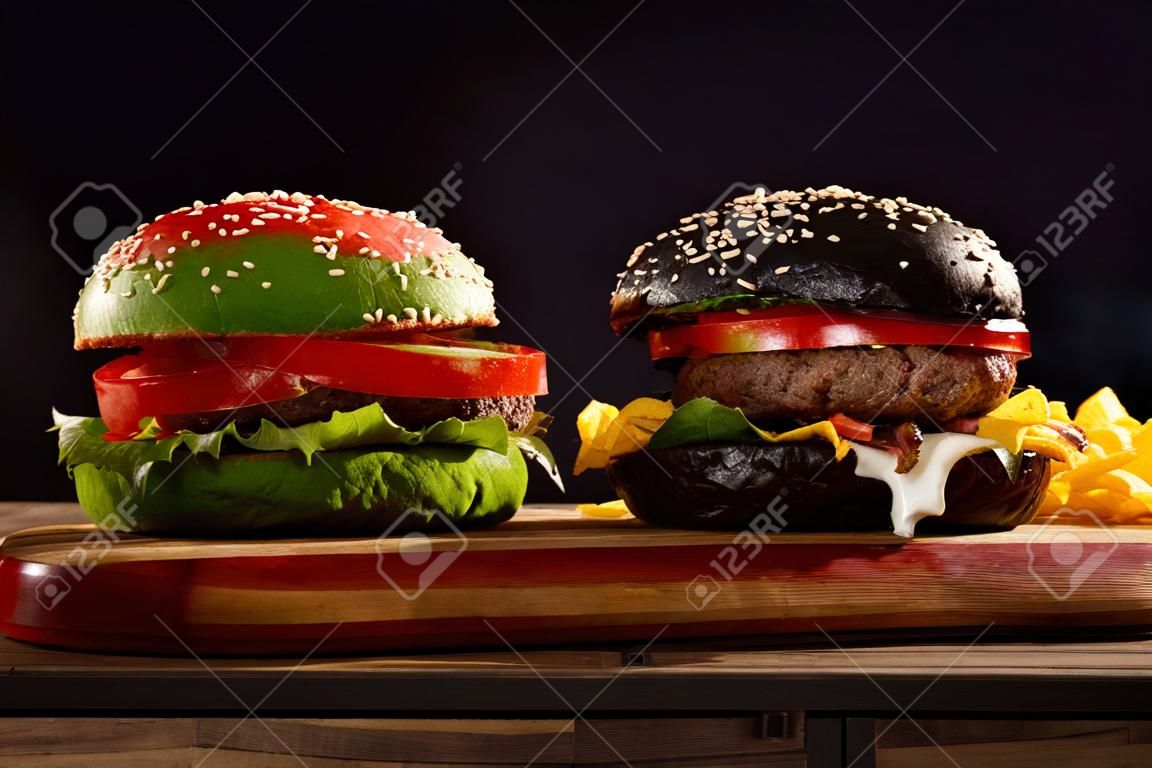 три, гамбургеры на красочных разведенных булочек в красном, зеленом и черном, давая различные варианты заполнения вид сбоку на деревянной доске