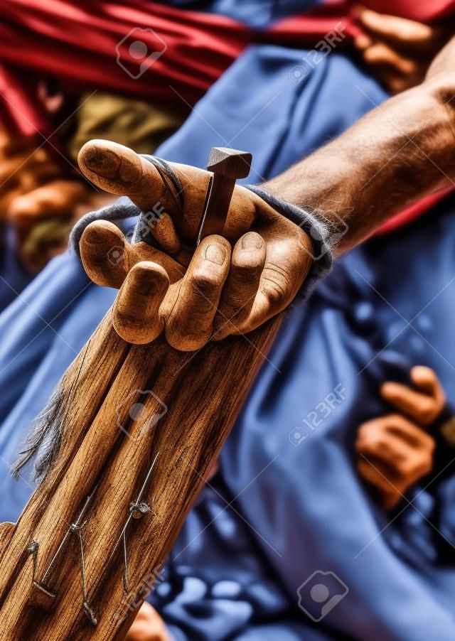 Reenactment of Jesus Christ crucifixion with human hand nailed to wooden cross in close up