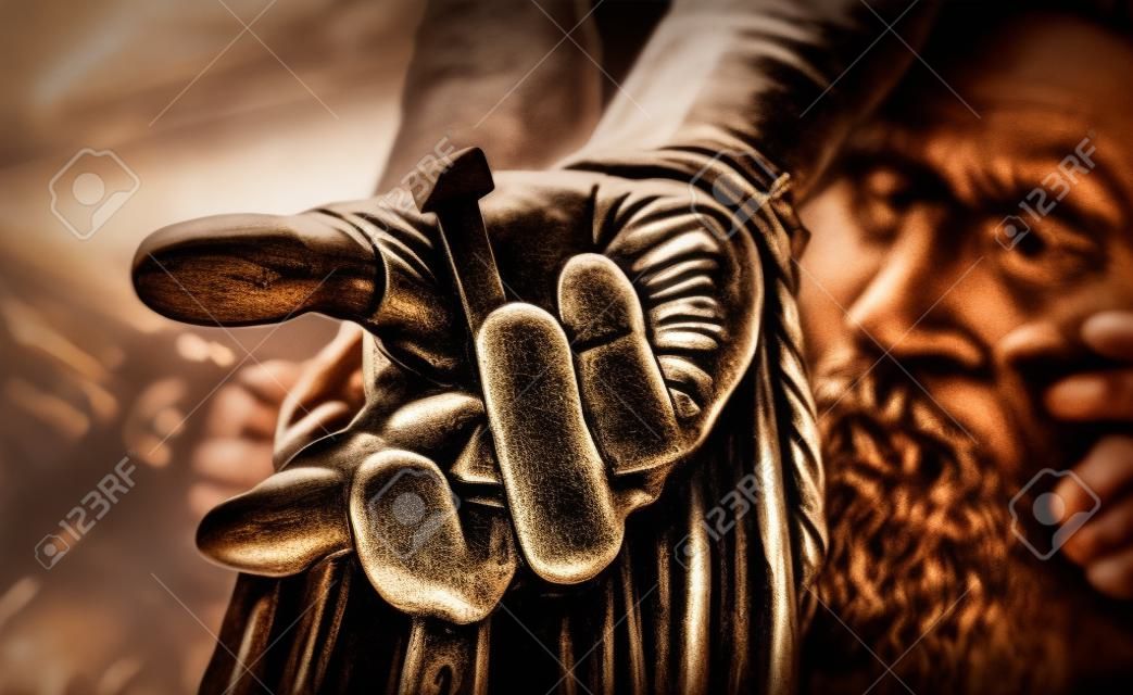Hand of Christ nailed to the cross with a close up view of a mans hand with an iron nail hammered through onto a wooden cross symbolic of the crucifixion of Christ at Easter