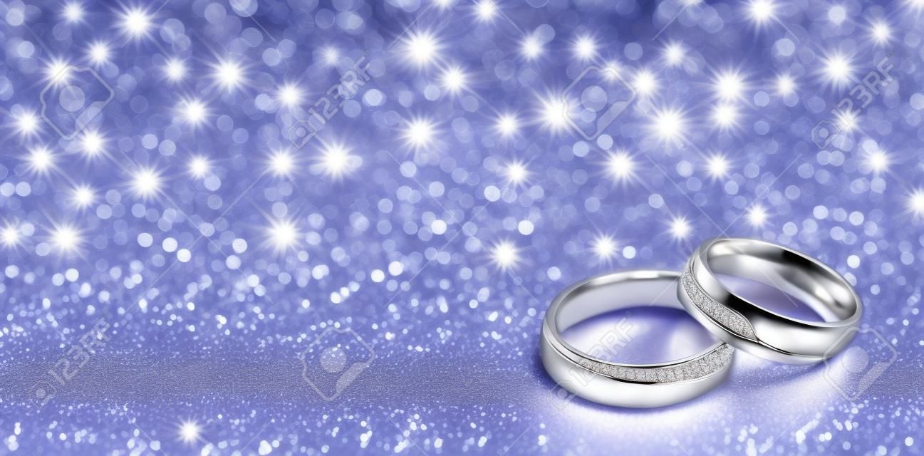 Anéis de casamento de designer no canto em um fundo brilhante cintilante em formato de banner panorâmico com espaço de cópia e foco seletivo