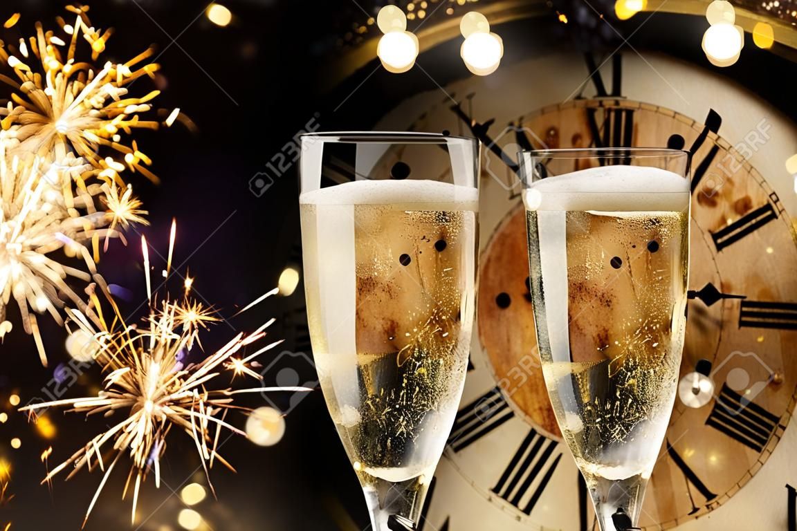 Fondo festivo de año nuevo con luces de Bengala y champán frente a un reloj de cuenta regresiva hasta la medianoche con un chispeante bokeh en la oscuridad