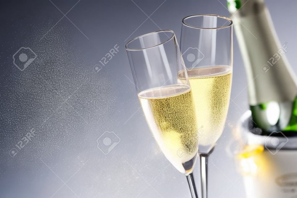 Zwei romantische Gläser funkelnder Champagner neben einer Flasche in einem Eiseimer- und Kopienraum, um eine Hochzeit, einen Jahrestag, ein neues Jahr oder einen Valentinstag zu feiern