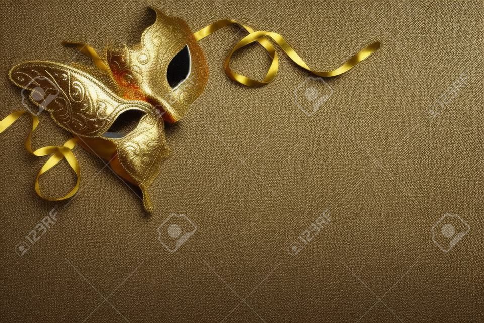 Srylischer metallischer goldener Mardi Gras- oder Karnevalsmaskenhintergrund auf einem strukturierten grauen Hintergrund mit Vignette