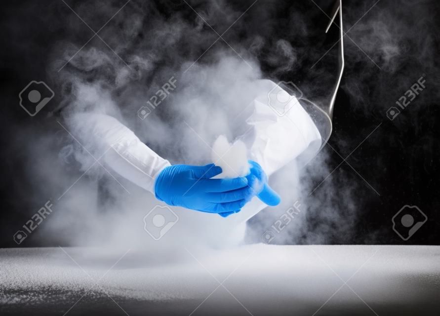 Trabajador de restaurante en traje negro y guantes de látex limpiando la harina blanca en polvo de las manos en forma rectangular
