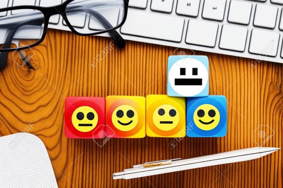 cubes with emoticons and computer keyboard on wooden background