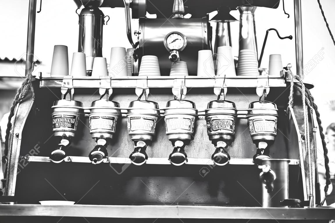 Barista vintage preparar café para el cliente en una máquina de estilo antiguo con aspecto retro hecho a mano y ropa retro en un puesto en el mercado al aire libre