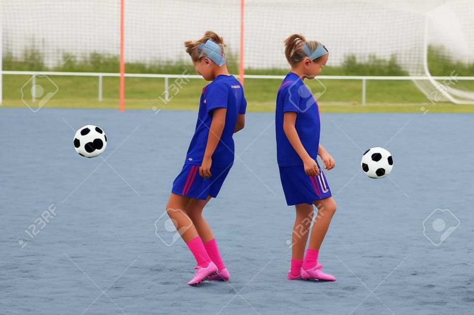 Two young girls playing soccer