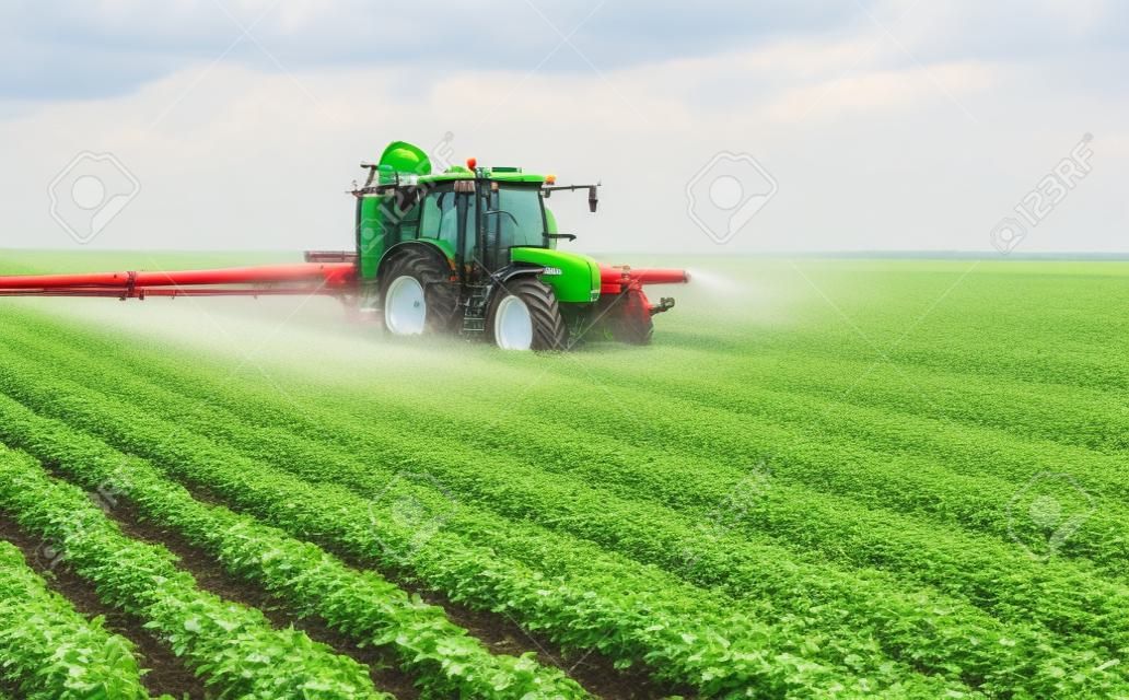Trattore che spruzza pesticidi sul campo di soia con spruzzatore a primavera at