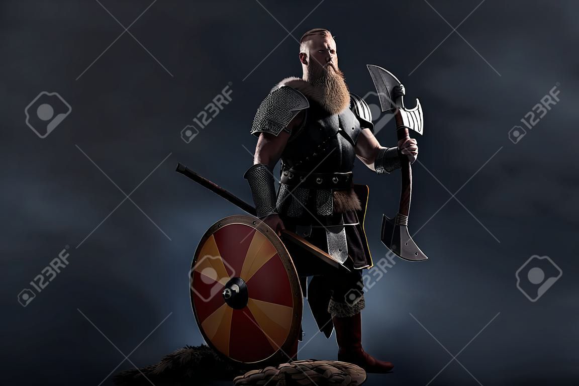 Medieval warrior berserk Viking with axes attacks enemy. Concept historical photo of Scandinavian god in armor and helmet with horns