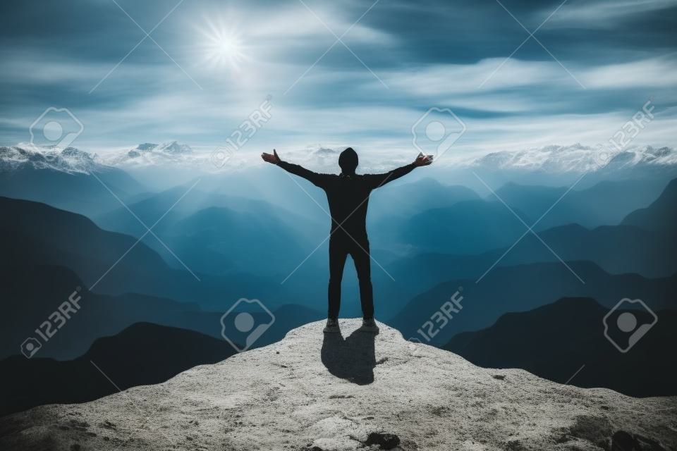 山の端に立っている男は、空中で腕を上げて勝利を感じています。