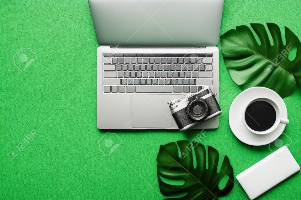 Traveler planning vacation trip and searching tourist attraction and information or booking hotel on laptop with accessories item women and map, old camera.  Top view and  leaf green background.  Travel concept