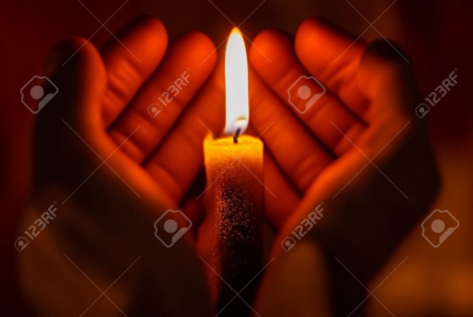 manos sosteniendo una vela encendida en la oscuridad