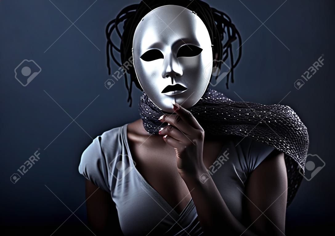 gloomy woman in silver mask posing on a black background.