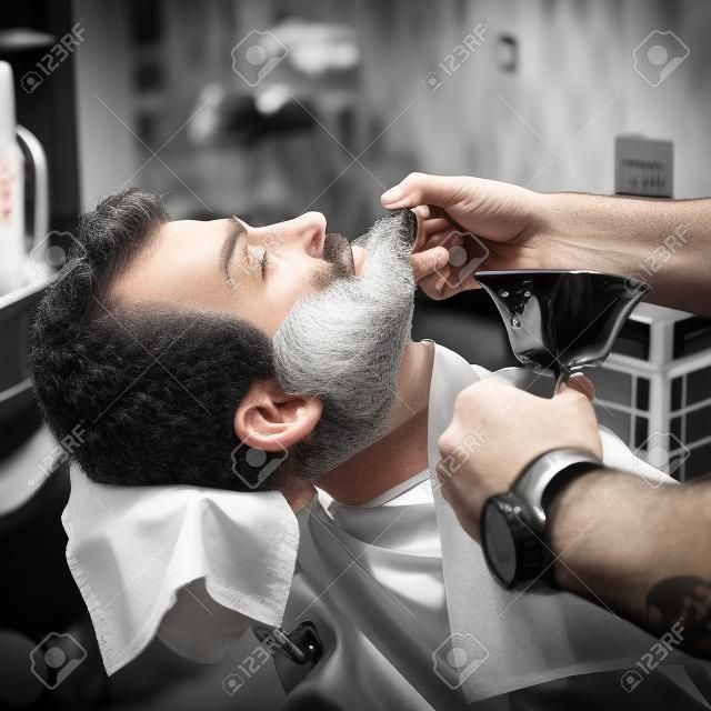 Correction de la barbe dans le salon de coiffure. Photographie noir et blanc.