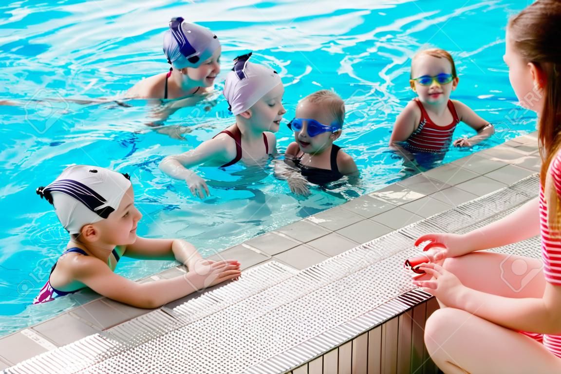 Enfants heureux enfants groupe à la classe piscine apprenant à nager