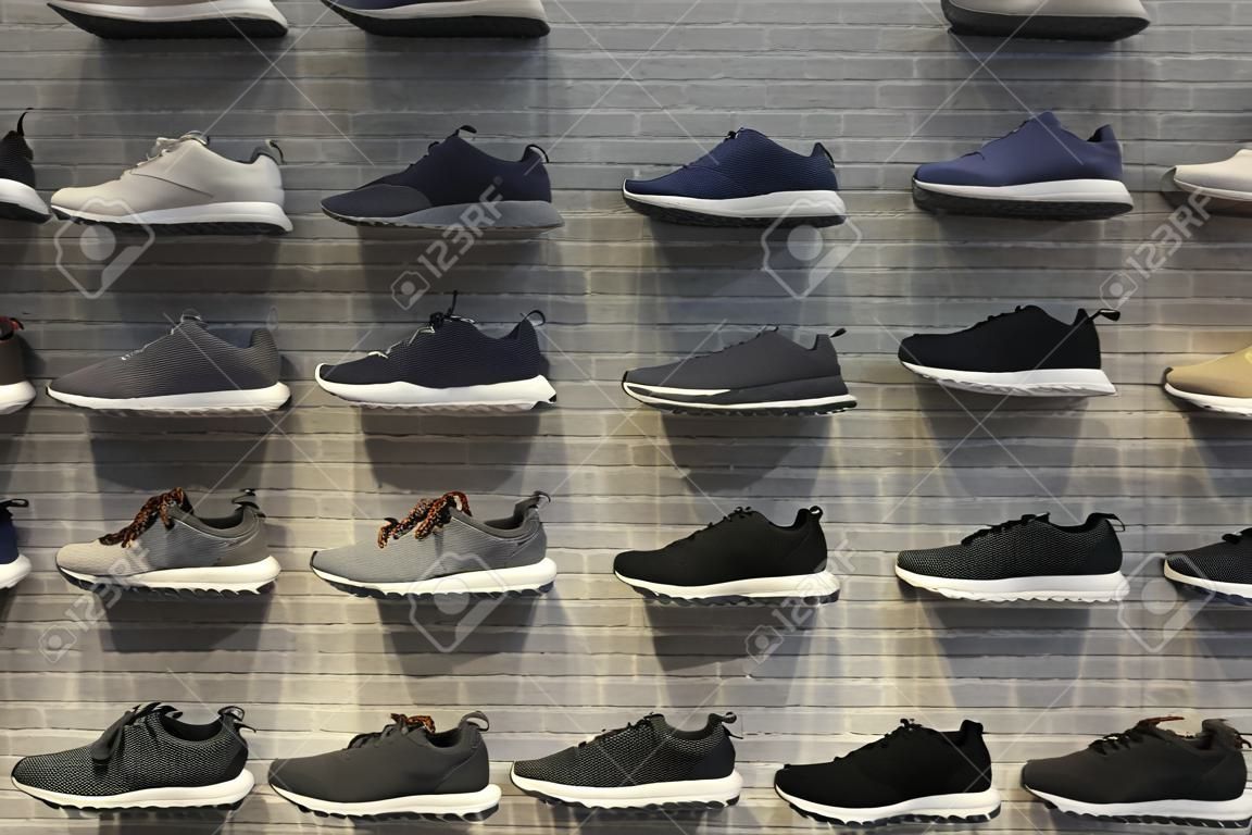 Shop display of unbranded modern new stylish sneakers running shoes for men on brick wall background texture.