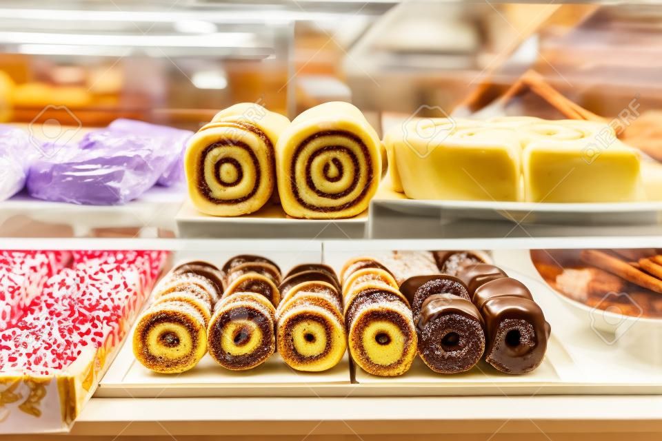 店の窓の菓子の様々な種類:シナモンロール、フルーツとドーナツとチーズケーキ
