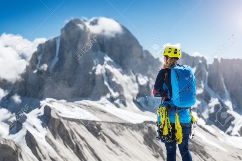 Alpiniste avec sac à dos, casque et harnais avec équipement d'escalade bénéficiant d'une vue imprenable sur le mont Tofana di Rozes avant l'ascension pendant la journée d'été dans les Alpes Dolomites - concept d'aventure