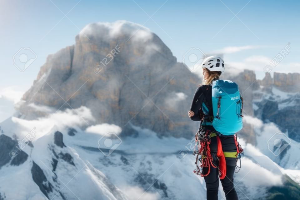 Alpinista femmina con zaino, casco e imbracatura con attrezzatura da arrampicata godendo di una vista mozzafiato sul monte Tofana di Rozes prima della salita durante la giornata estiva nelle Alpi dolomitiche - concetto di avventura