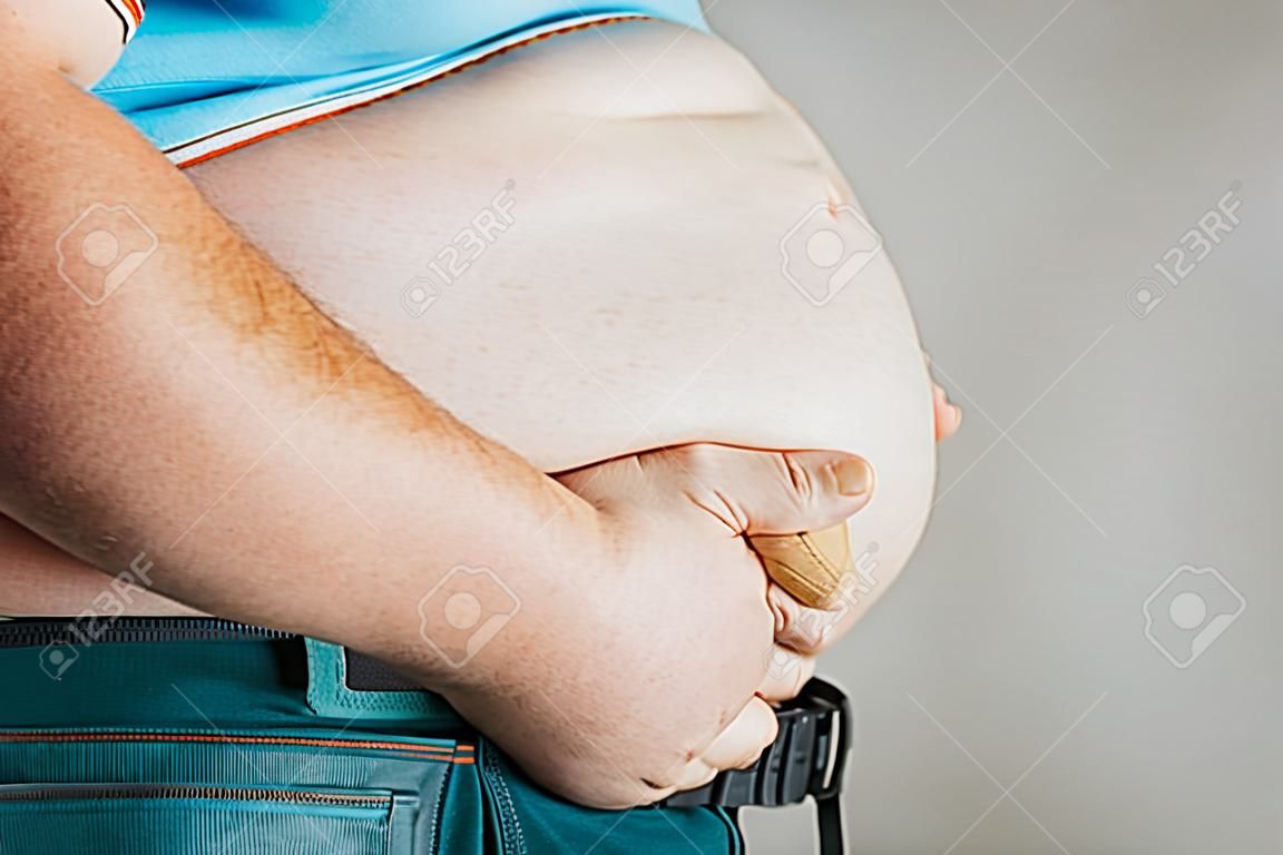 Sovrappeso del corpo di una persona con le mani che toccano l'addome. Il concetto di obesità.