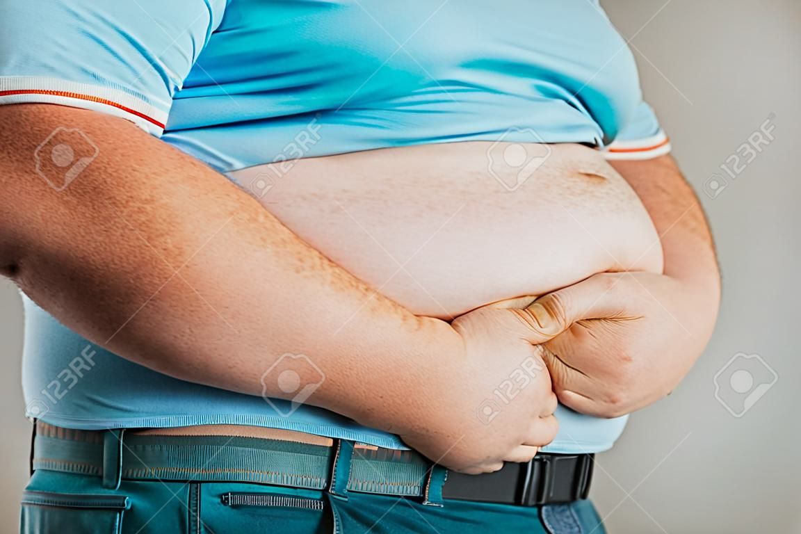복부에 손을 대고 있는 사람의 과체중입니다. 비만의 개념입니다.
