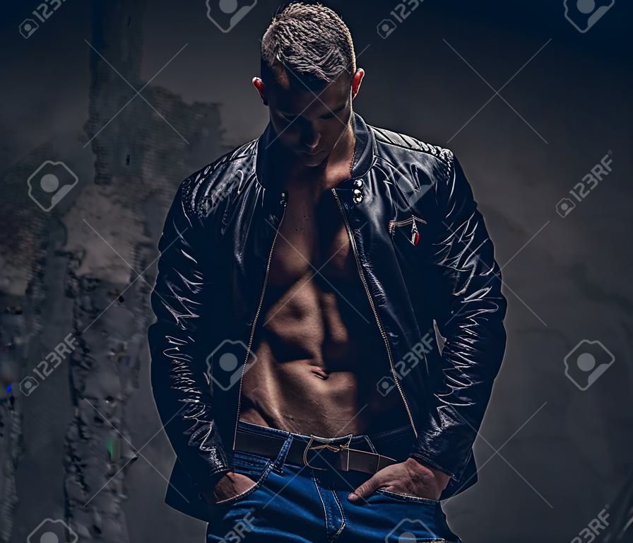 청바지와 벗은 몸에 착용하는 블랙 재킷에 근육 남성. 회색 배경에 고립.