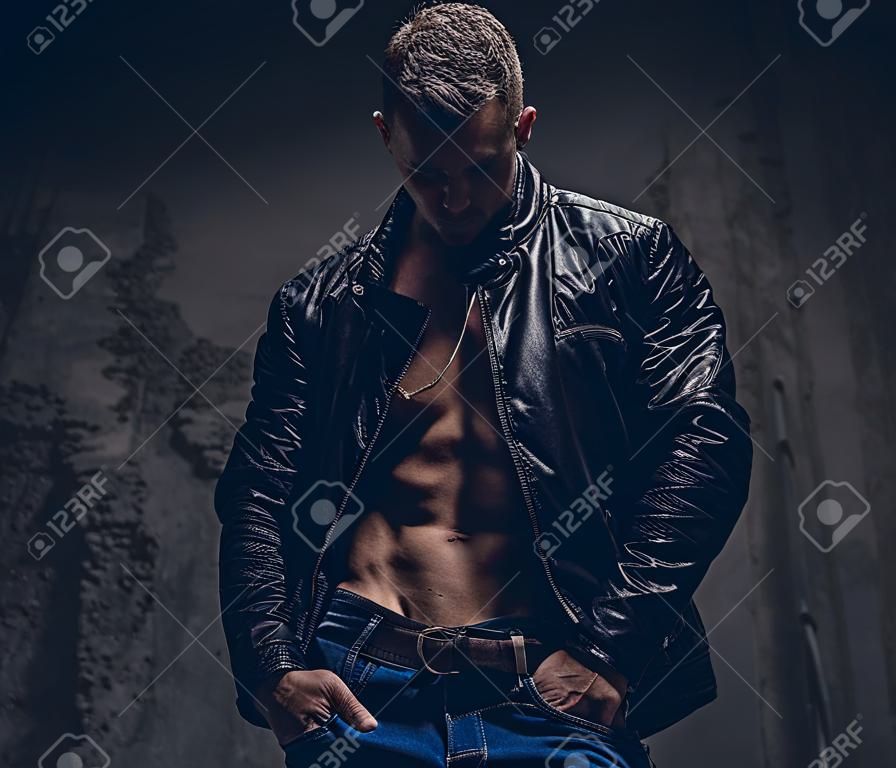 ブルー ジーンズと上半身裸の体に身に着けている黒いジャケットで筋の男性。灰色の背景上に分離。