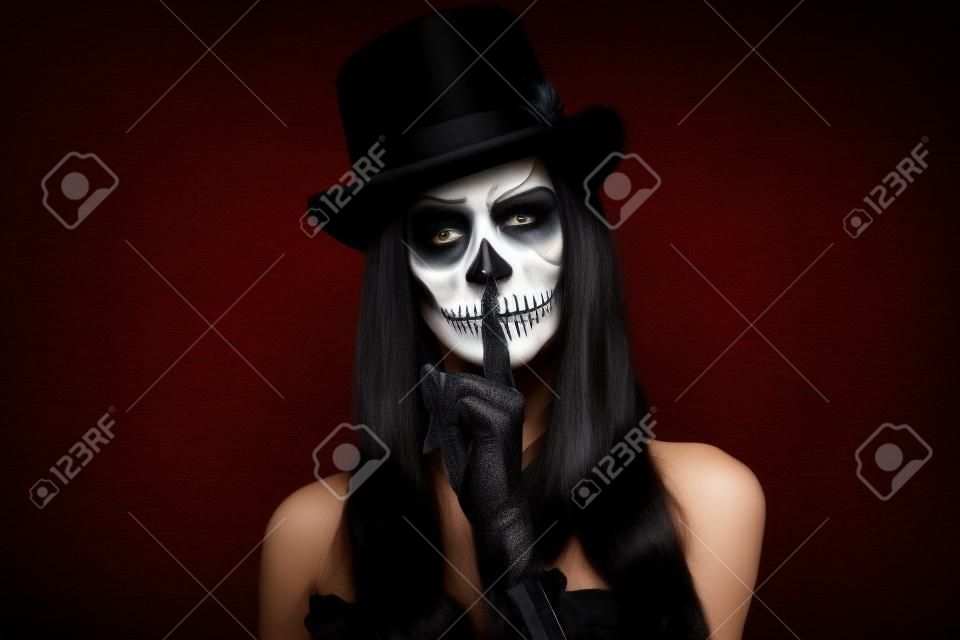 Mulher em silêncio de Halloween. Uma mulher em chapéu de topo e crânio compõem.