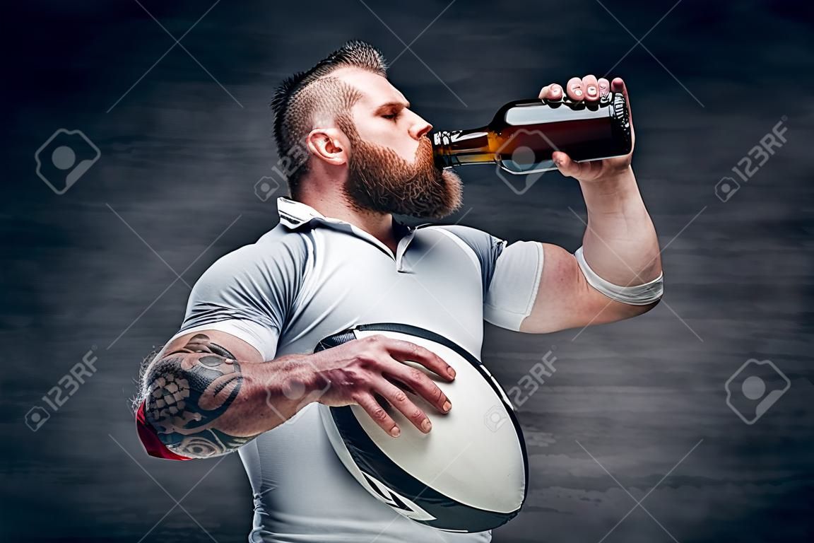 Brutal rugby player drinking beer.